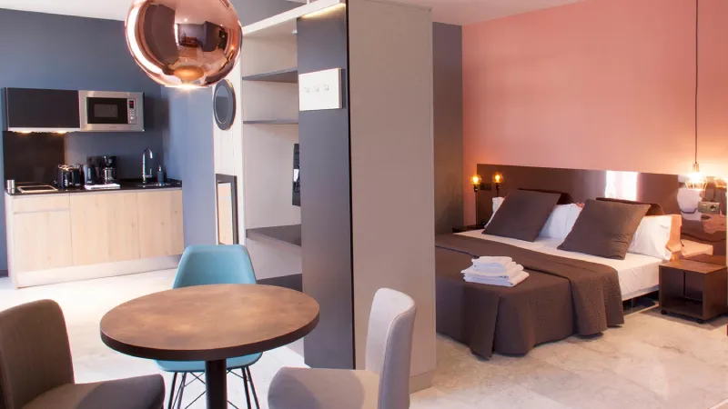 Suite moderna con cocina integrada, cama doble y decoración minimalista.