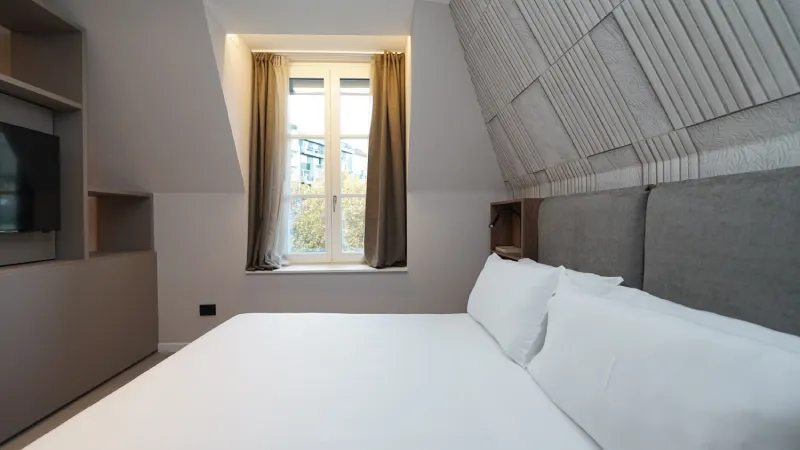 Habitación moderna con cama blanca, ventana y paredes decorativas.