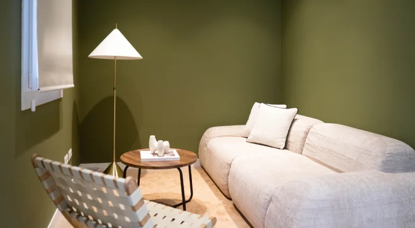 Habitaci&oacute;n con sof&aacute; blanco, mesita redonda y l&aacute;mpara junto a ventana
