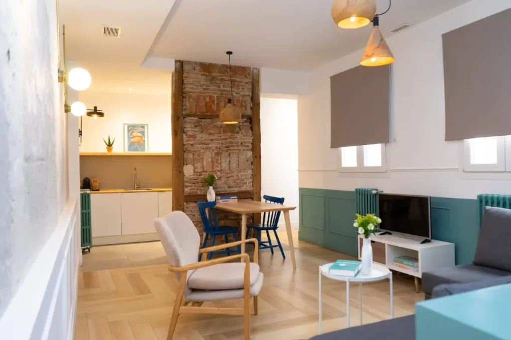 Sala de estar moderna con cocina abierta, mesa de comedor, sofá y televisión.