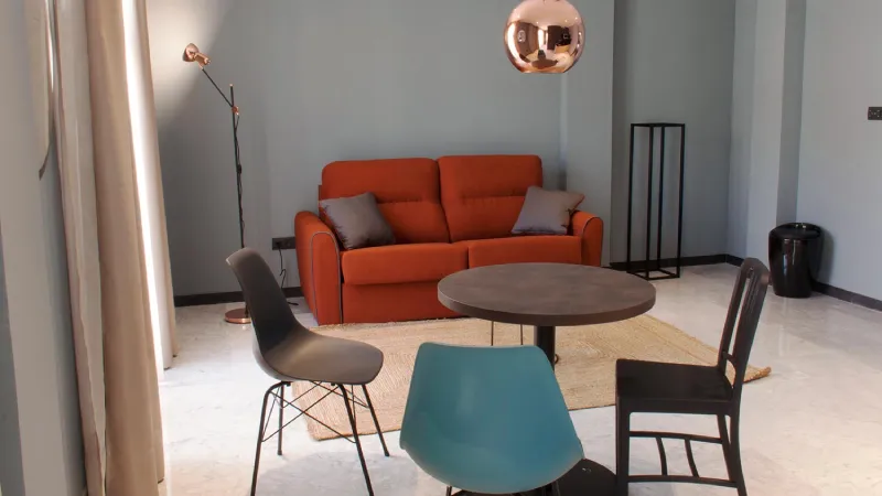 Sala moderna con sofá naranja, mesa redonda y sillas de diseño.