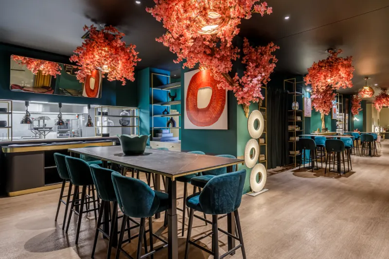 Salle de restaurant avec décor floral rose et mobilier élégant, ambiance moderne et chaleureuse.