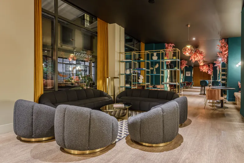 Intérieur d'un salon moderne avec des fauteuils gris et une décoration florale rose.