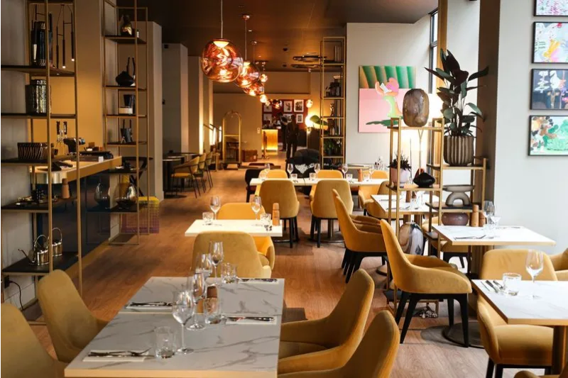 Salle de restaurant moderne avec chaises jaunes et tables en marbre.