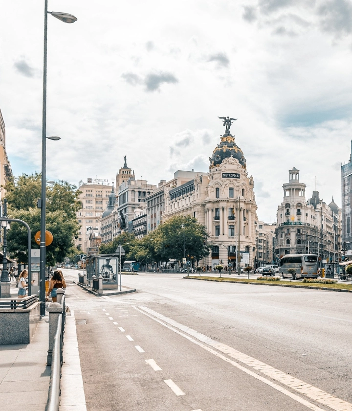 Calle concurrida en una ciudad europea con edificios históricos y un cielo nublado.