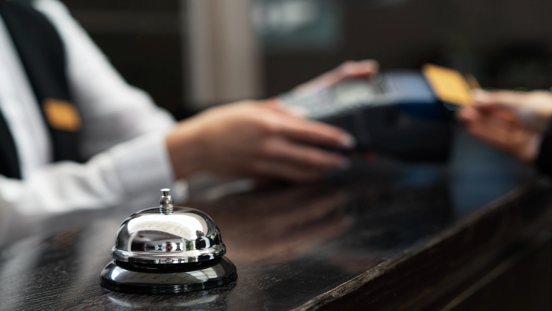Campana de mostrador y pago con tarjeta en recepción de hotel.