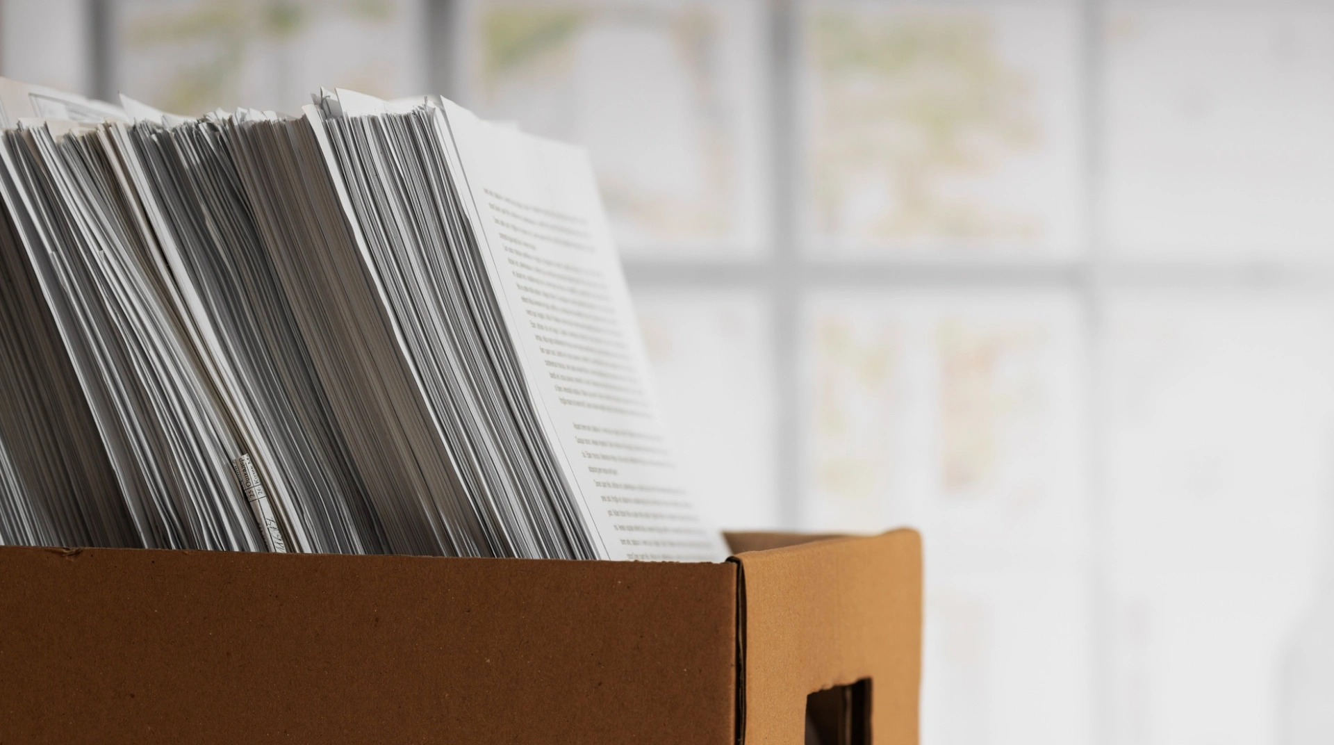 Una caja marrón llena de hojas de papel impresas en posición vertical.