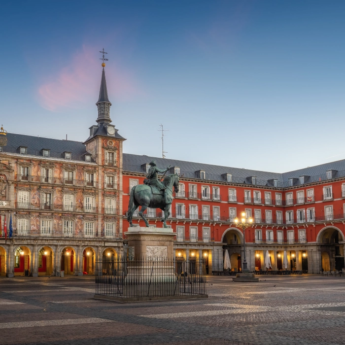Plaza Mayor de Madrid con estatua ecuestre al amanecer, destacando su arquitectura histórica.
