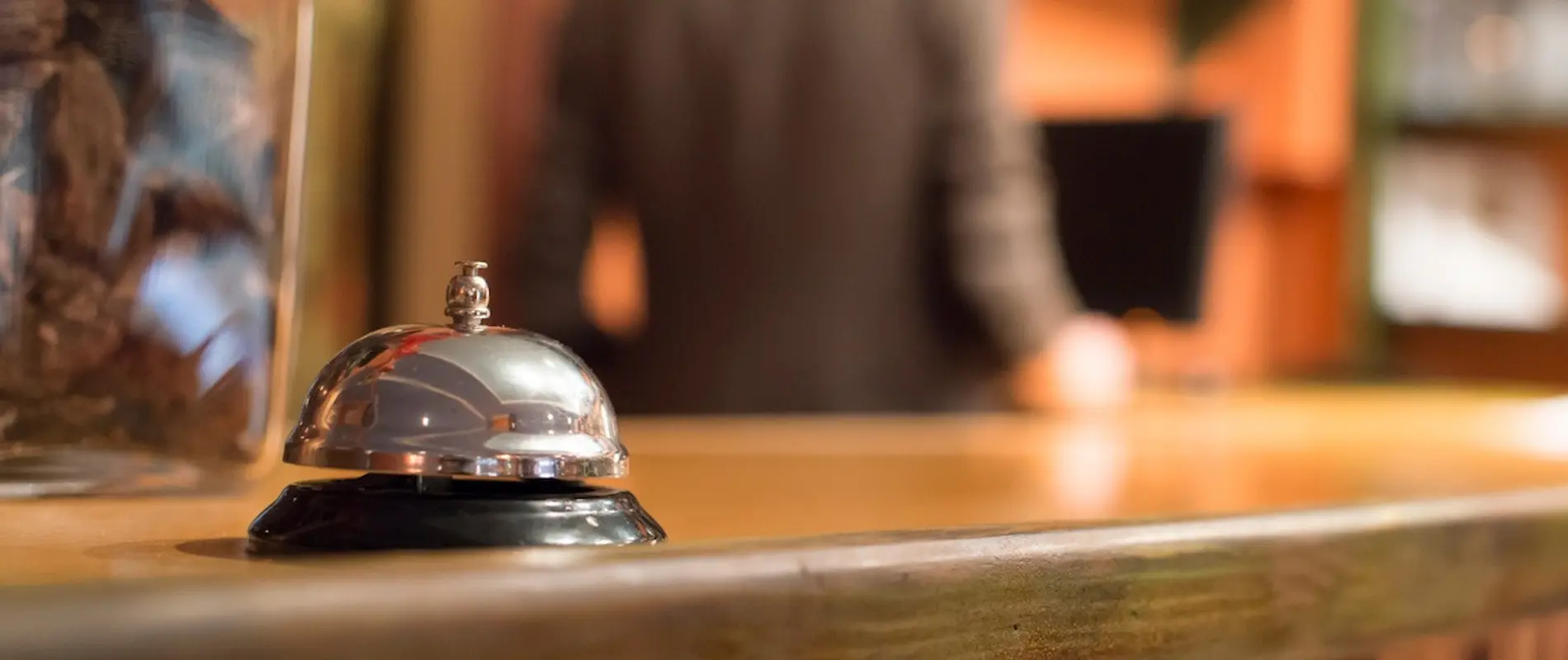 Timbre de recepción en un mostrador de hotel, con una persona de fondo.