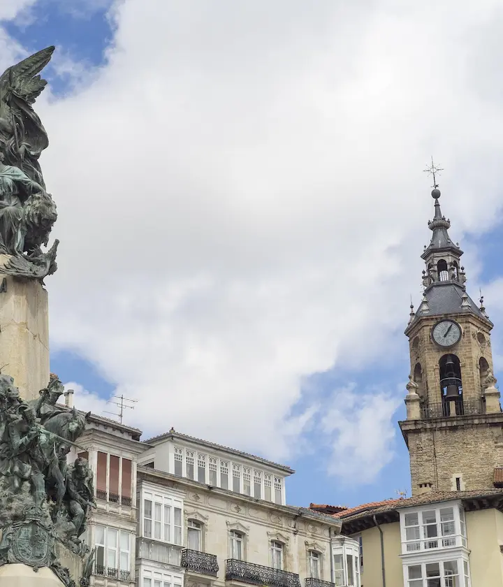 Torre del reloj y edificios históricos bajo un cielo parcialmente nublado.