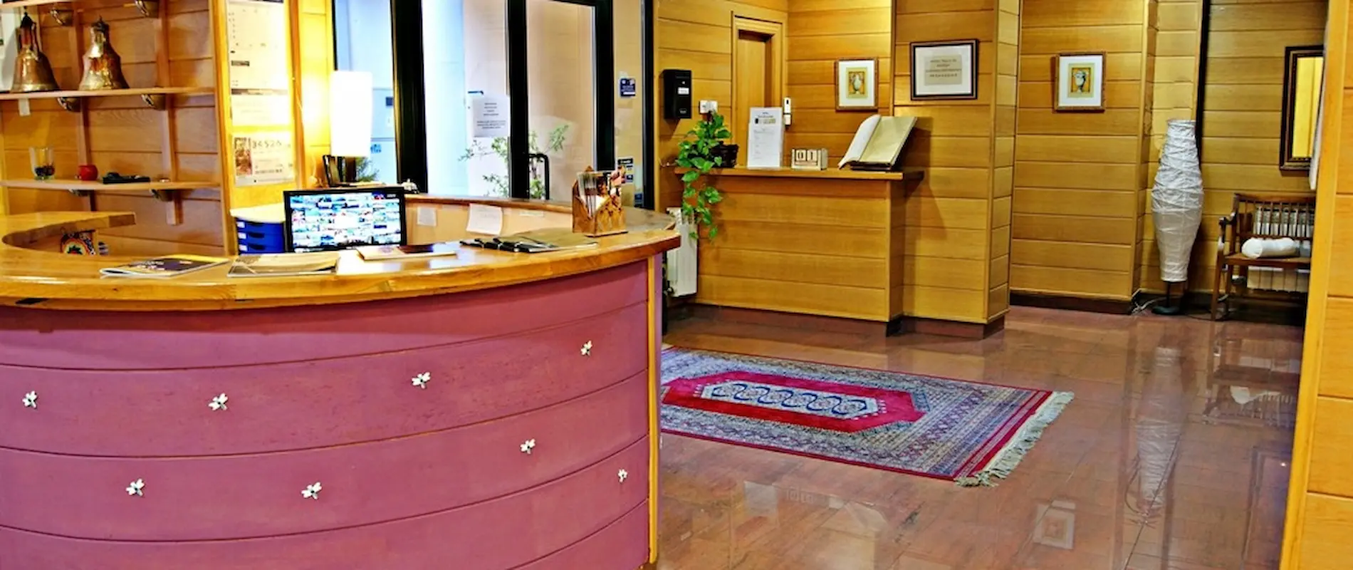 Mostrador de recepción de hotel con decoración de madera y alfombra colorida en el suelo.