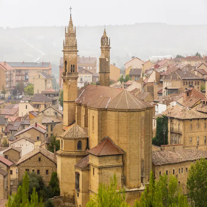 Iglesia antigua rodeada de casas en un pueblo con niebla en el fondo.