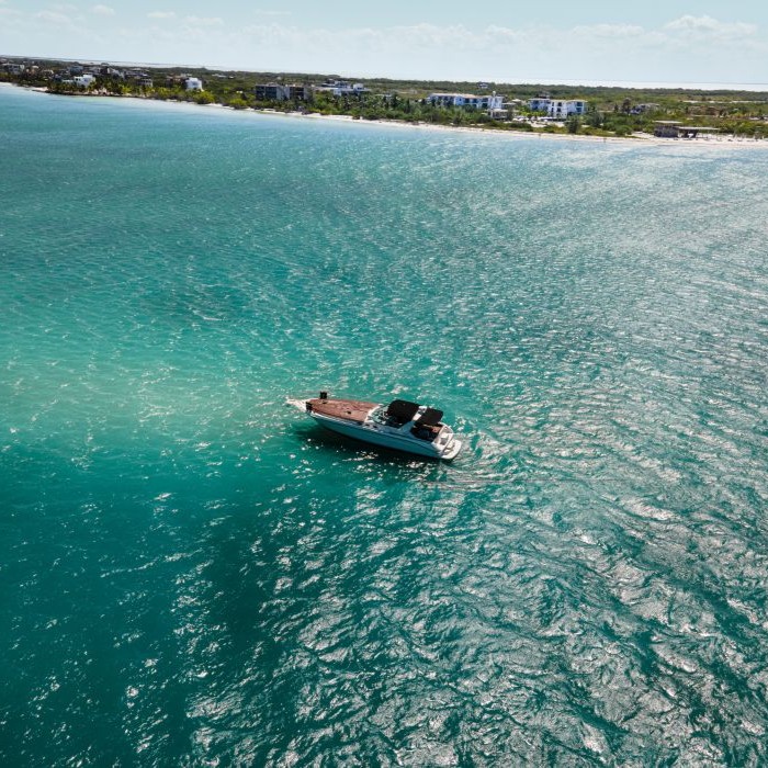 Boat floating on turquoise water near a distant shoreline.