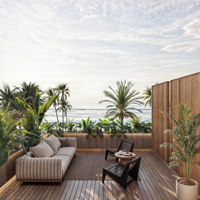 Outdoor patio with a sofa, chairs, and plants overlooking tropical palm trees and ocean views under a cloudy sky.