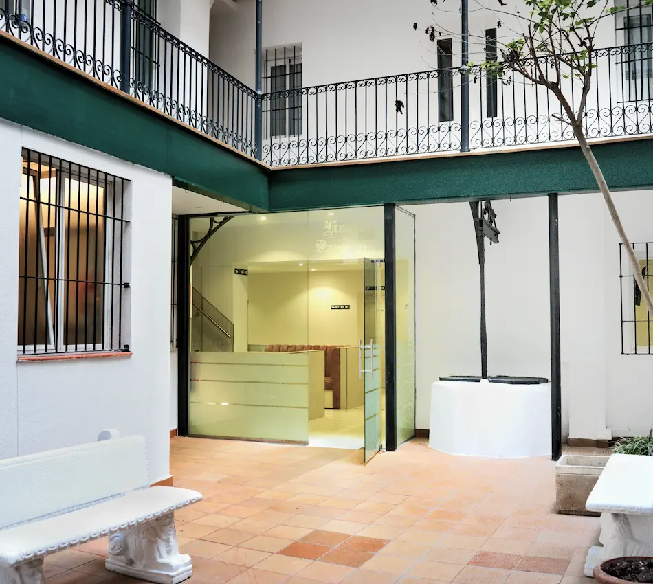 Patio interior con banco, pozo y puerta de cristal.