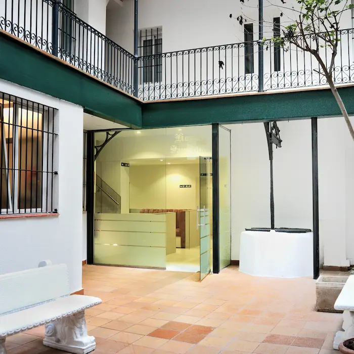 Patio interior con suelo de baldosas, puerta de vidrio y pozo blanco.