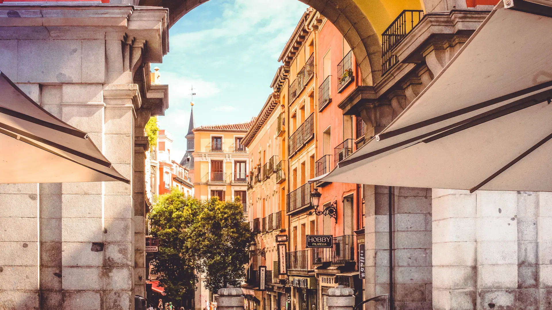 Calle estrecha con edificios coloridos vista desde un arco, bajo un cielo despejado.