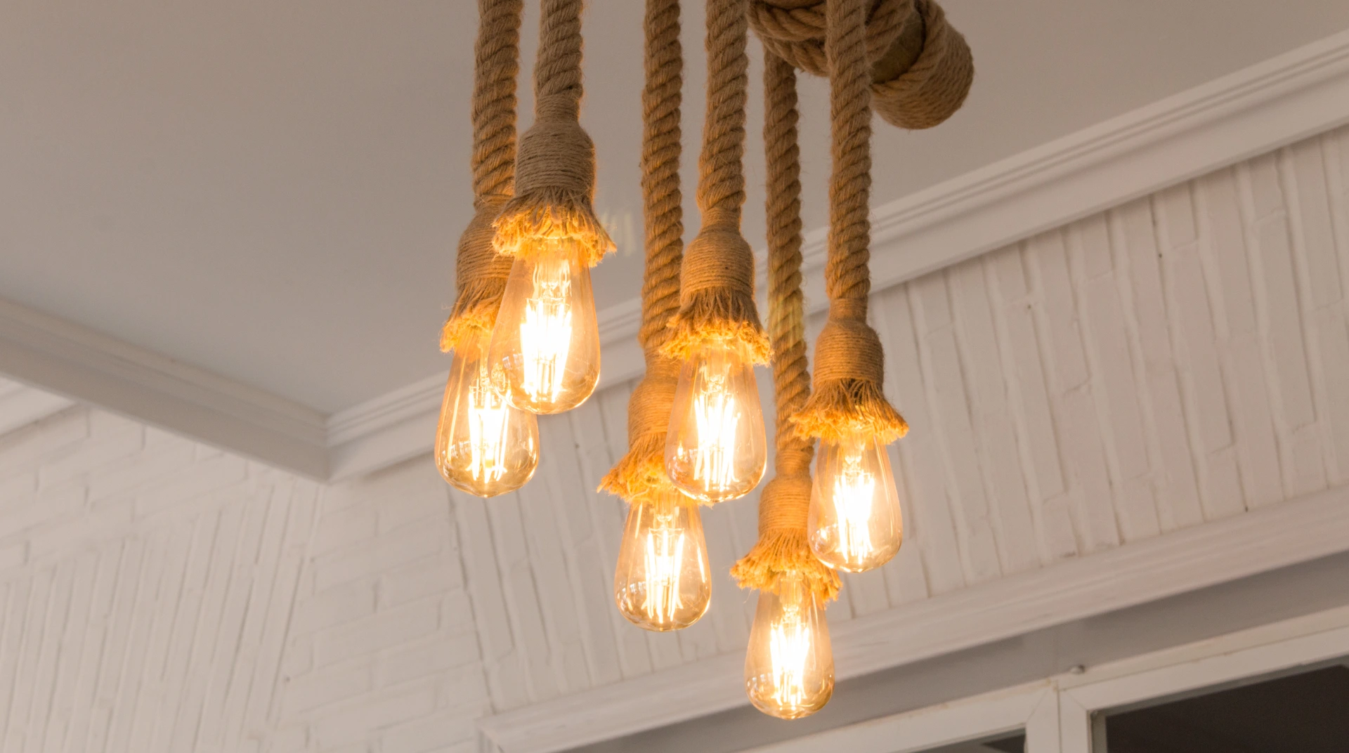 Lámparas colgantes de estilo vintage con cuerdas de yute iluminando un techo blanco.