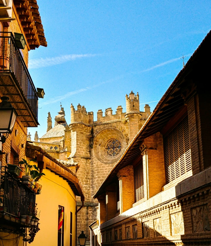 Calle estrecha con vista a una catedral gótica bajo un cielo azul.
