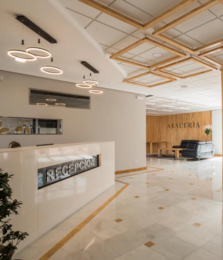 Vestíbulo moderno con mostrador de recepción y sala de espera con sofás en fondo de madera.