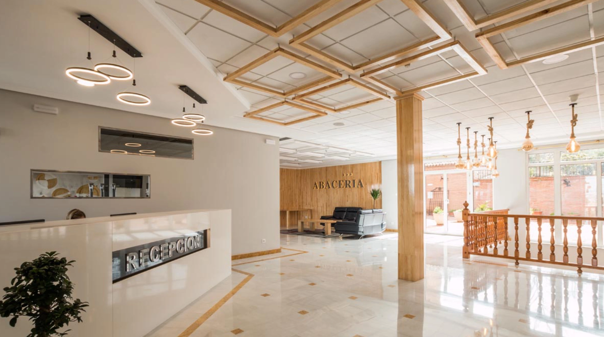 Recepción moderna con lámparas colgantes y muebles de madera en un vestíbulo elegante y luminoso.