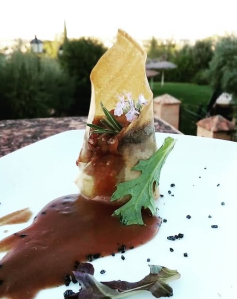 Plato elegante de cocina gourmet con salsa y brotes en un entorno al aire libre.