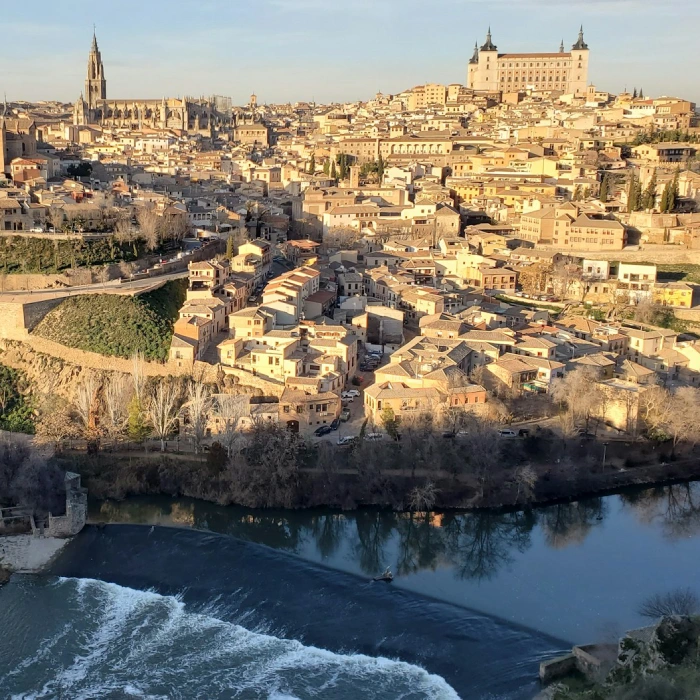 Vista panorámica de una ciudad histórica con un río en primer plano y edificios antiguos.