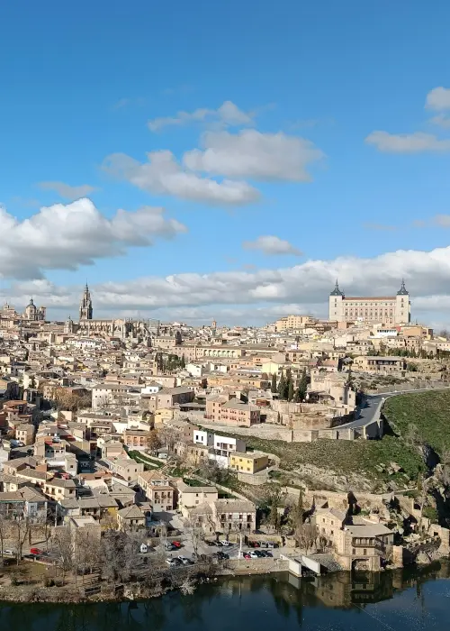 Vista panorámica de Toledo, España, con edificios históricos y cielo azul con nubes.