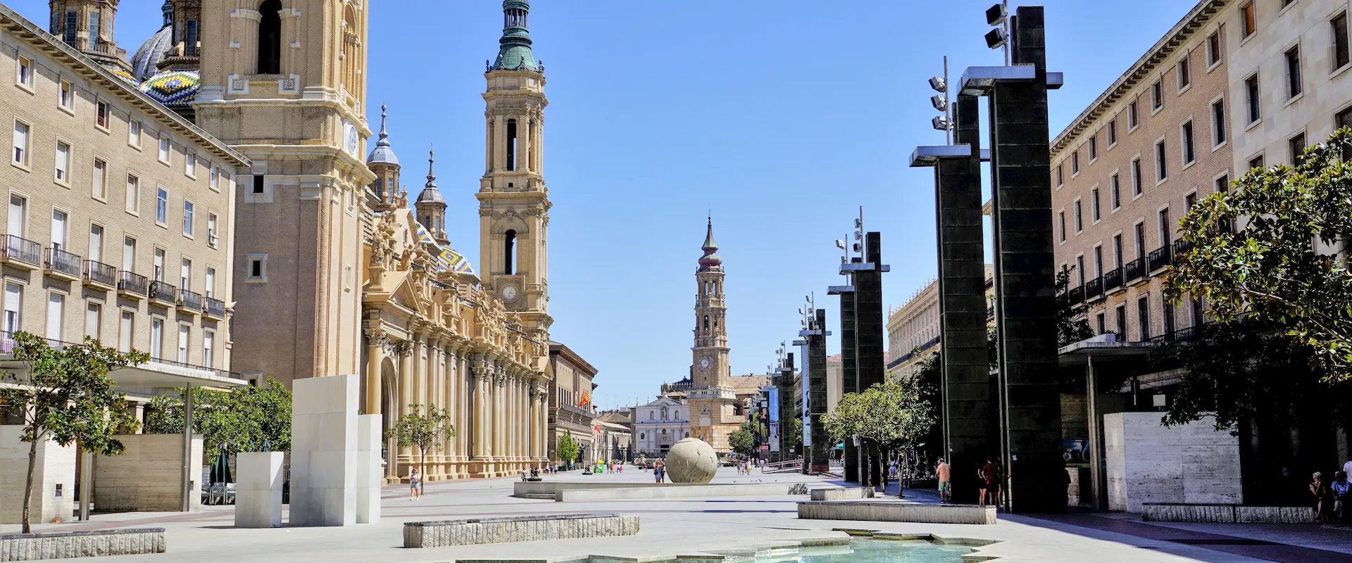 Plaza amplia con edificios históricos y columnas modernas bajo un cielo despejado.