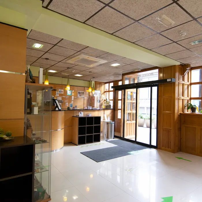 Recepción de hotel con decoración moderna y luminosa, mostrando el mostrador y puertas de entrada.