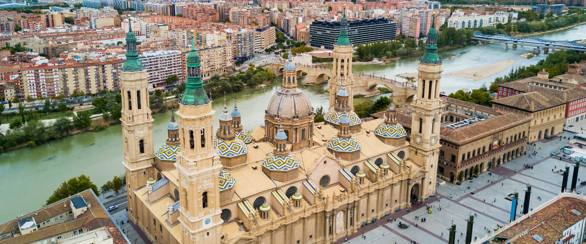Vista aérea de la Basílica del Pilar en Zaragoza, junto al río y edificios urbanos.