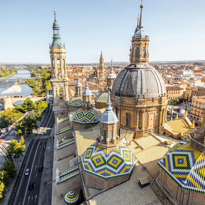 Cúpulas multicolores de una catedral con un río y una ciudad al fondo bajo un cielo despejado.