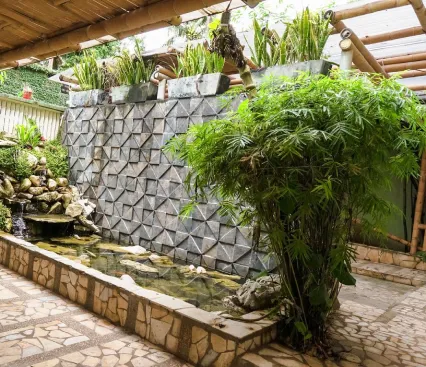 Jard&iacute;n interior con plantas, una fuente de piedra y un estanque peque&ntilde;o.
