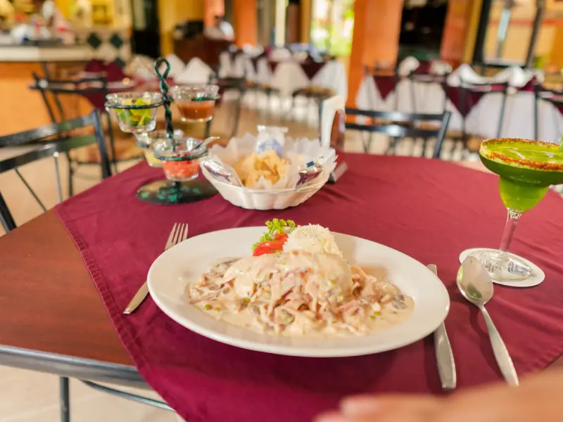 Plato de comida con bebida verde en mesa, fondo de restaurante desenfocado.
