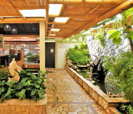 Espacio interior con jard&iacute;n tropical, estanque y techo de bamb&uacute;. Ambiente natural y relajante.