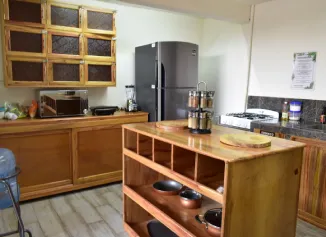 Cocina con refrigerador, estufa, repisa de madera con ollas y utensilios en un ambiente ordenado.