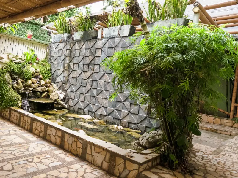 Patio interior con fuente de agua, paredes de piedra y plantas decorativas.