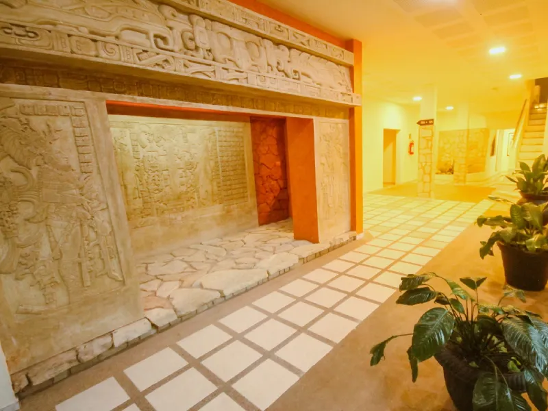 Pasillo con decoraci&oacute;n de relieves antiguos en las paredes y plantas en macetas.