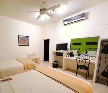 Habitaci&oacute;n de hotel con dos camas, televisor, escritorio, silla y aire acondicionado.