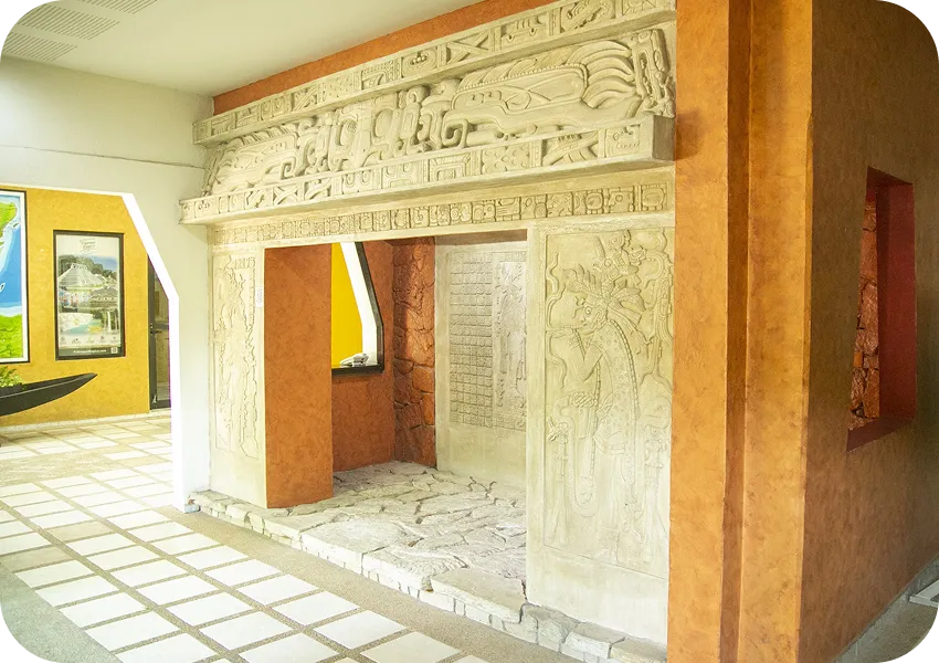 Relieve enmarcado en una pared naranja con inscripciones y dise&ntilde;os en una sala interior.