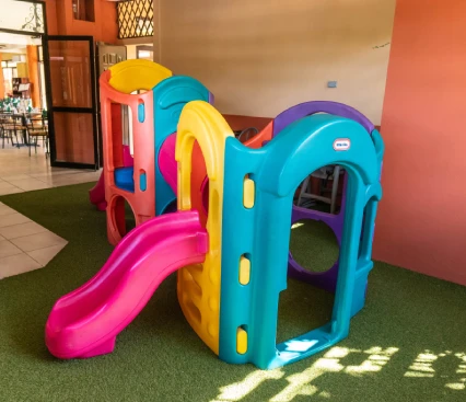 Estructura de juegos infantil de pl&aacute;stico colorida con tobog&aacute;n en una &aacute;rea con c&eacute;sped artificial.