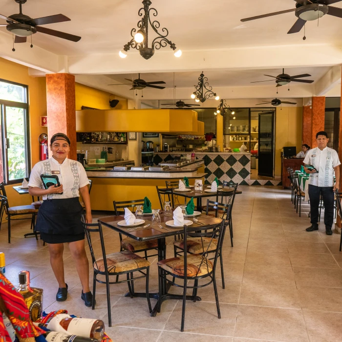 Restaurante acogedor con mesas preparadas y dos empleados listos para atender.