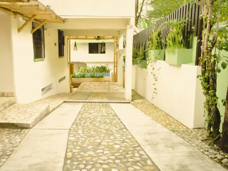 Entrada a una casa con camino de piedra y plantas en las paredes laterales.
