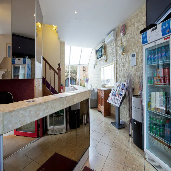 Réception d'un hôtel avec escalier, frigo de boissons et brochures.