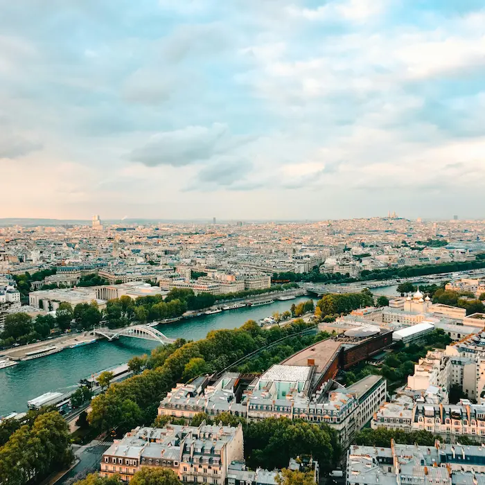 Vue aérienne d'une ville avec fleuve, ponts et bâtiments sous un ciel nuageux.