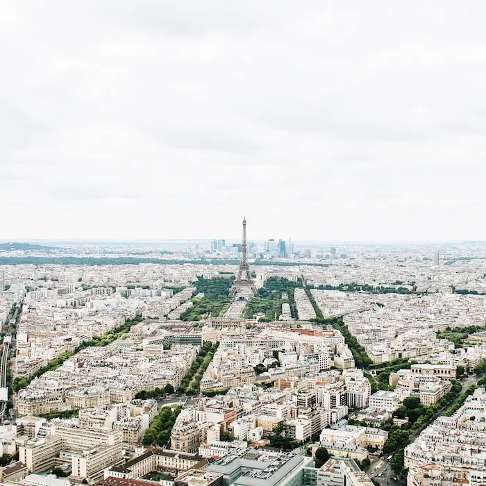 Vue aérienne de Paris avec la Tour Eiffel au centre sous ciel nuageux.