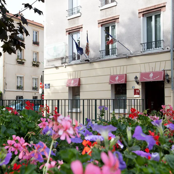 Fleurs colorées devant un bâtiment avec des drapeaux et auvents rouges.