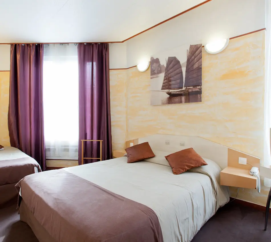 Chambre d'hôtel avec lit double, rideaux violets et décor nautique au mur.