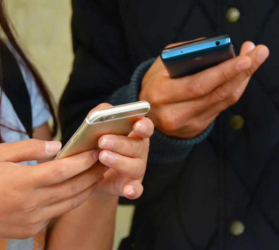 Deux personnes tenant et utilisant des smartphones.