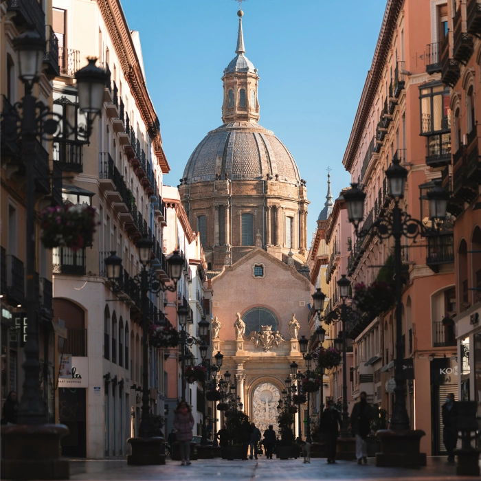 Calle c&eacute;ntrica con catedral al fondo, edificios a los lados y cielo despejado.